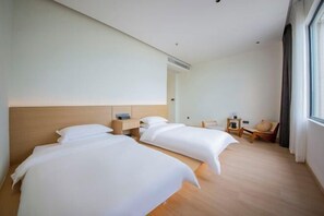 A hotel room with two beds, wooden flooring, a small table, and a chair. - Lanting Holiday Villa (Putian)