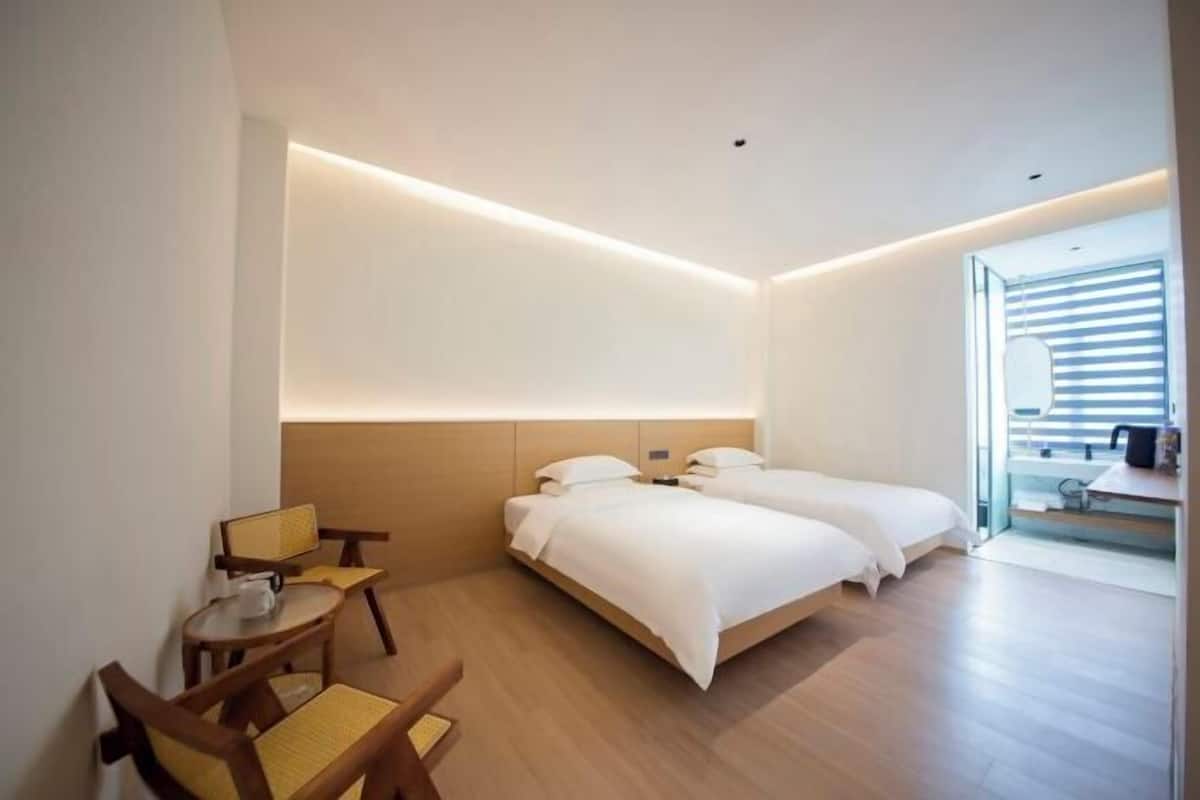 A modern hotel room with a bed, a desk, a chair, and a small table.