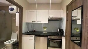 Una cucina moderna con mobili bianchi, un frigorifero in acciaio inossidabile, un forno e una macchina per il caffè.