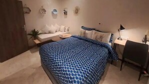 Una camera da letto moderna con un letto, un comodino, una sedia e una scrivania con una lampada.