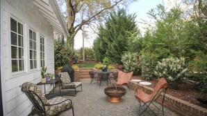 A patio with a fire pit, outdoor furniture, and a brick wall.