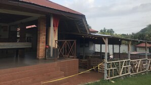 A building with a corrugated metal roof, brick walls, and a covered outdoor area with wooden pallets. - Whispers  Guest House  (Kumasi)