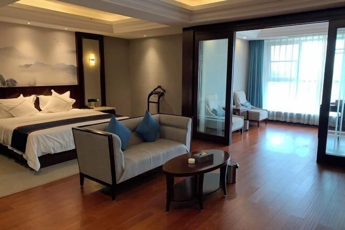 Una habitación de hotel con una cama, un sofá, una mesita y una silla.