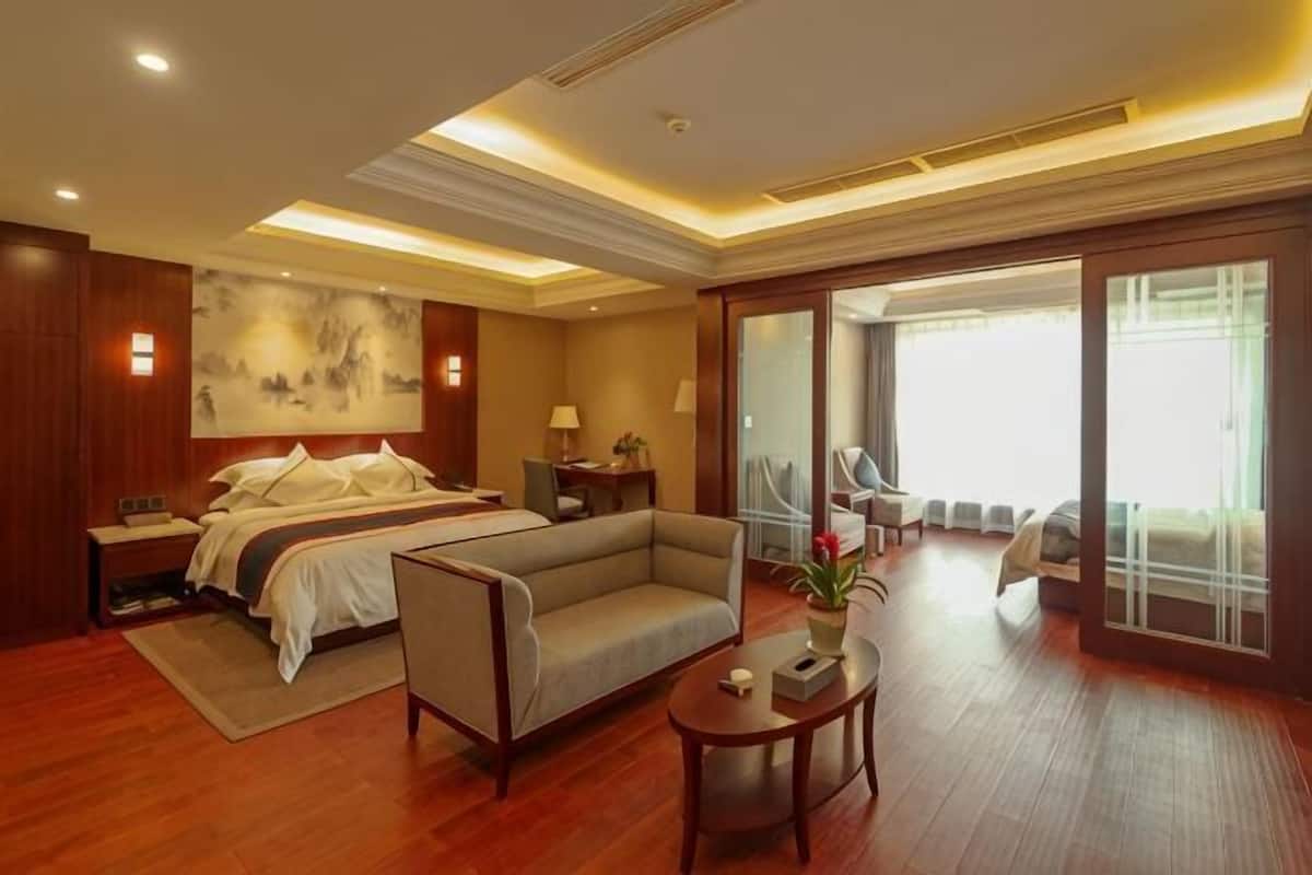 Habitación de hotel con cama, sofá, mesa y vistas al exterior.