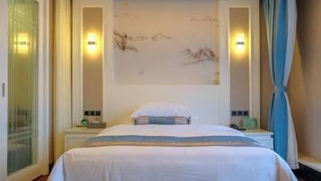 Une chambre d’hôtel avec un lit, des tables de chevet, une œuvre d’art accrochée au mur et une fenêtre avec des rideaux.