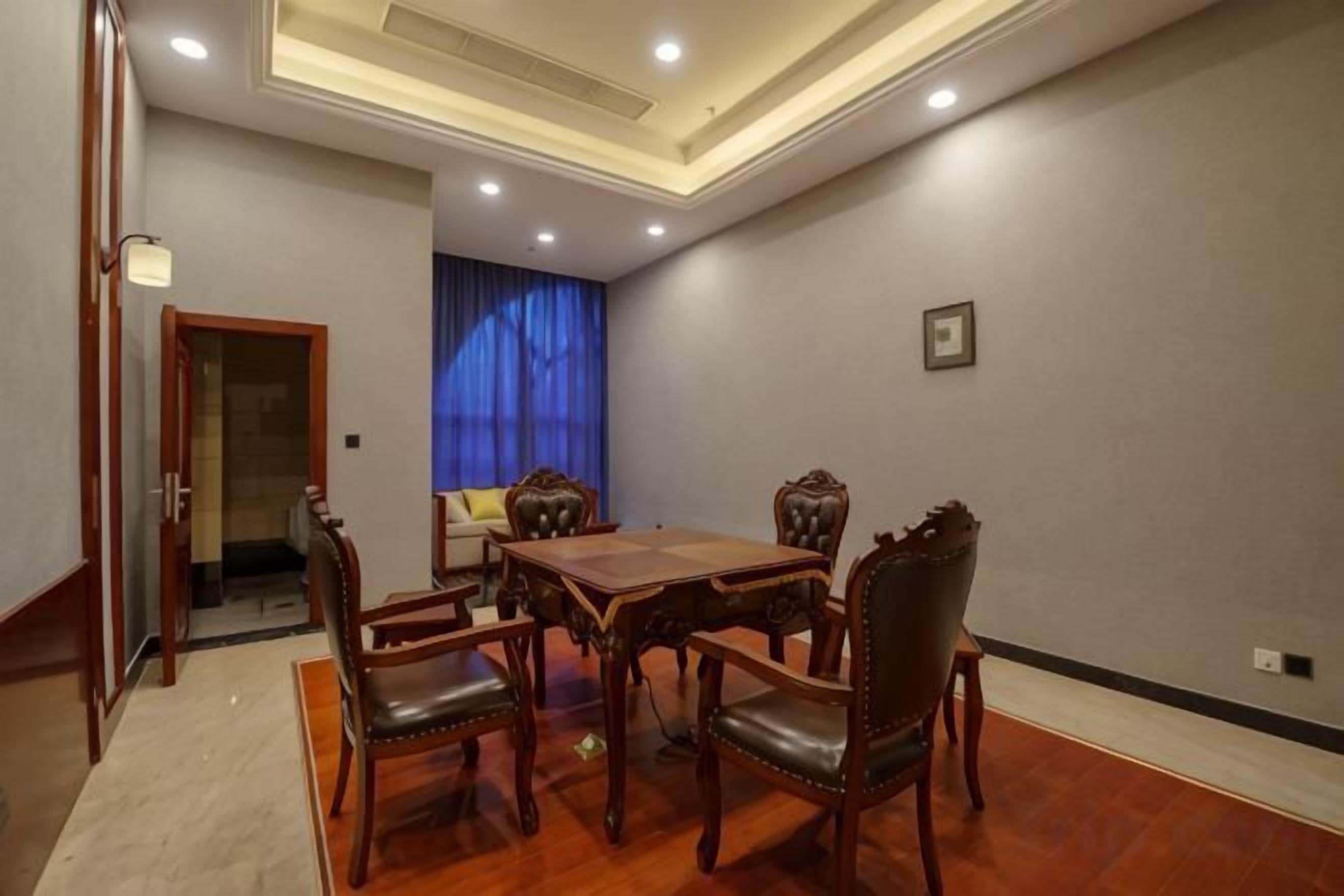 Un salón de conferencias con una mesa y sillas de madera, un sofá y una cortina azul.