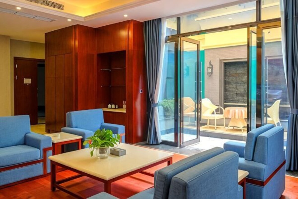 Een hotel lobby met blauwe zitplaatsen, een bijzettafeltje, houten lambrisering en uitzicht door glazen deuren.