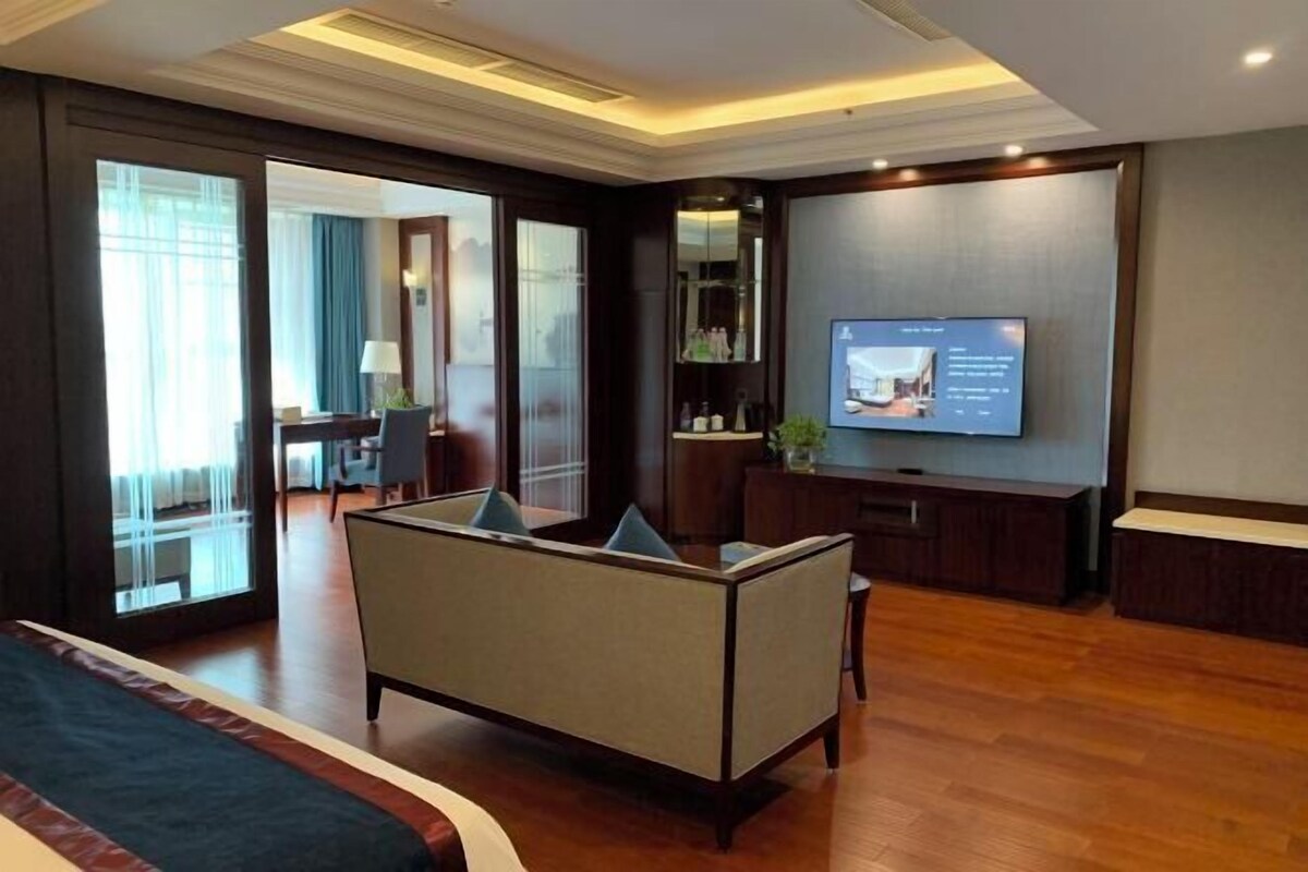 Une chambre d’hôtel avec un grand lit, un canapé, une télévision et un bureau.