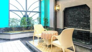 A room with a fireplace, a window with a unique design, and wicker furniture. - Jiu Long Ying Bin Hotel (Yibin)