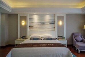 Une chambre d’hôtel avec un lit, des tables de chevet, une chaise et un mur orné d’un tableau.