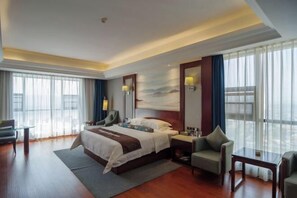 Une chambre d’hôtel moderne, dotée d’un grand lit, d’un bureau, d’une chaise et d’une grande fenêtre avec des rideaux.