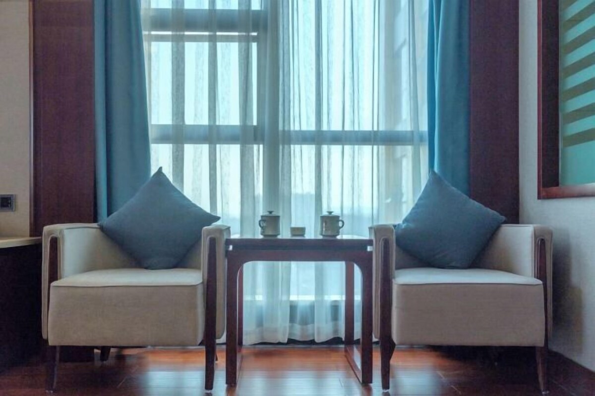 Une pièce avec deux canapés, une petite table et une fenêtre avec des rideaux.