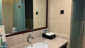 A modern bathroom with a large mirror, a sink, and a glass shower enclosure.