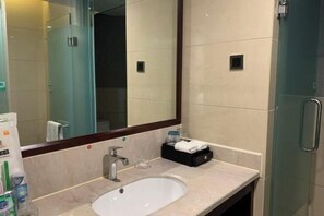 Een moderne badkamer met een grote spiegel, een wastafel en een douchecabine van glas.