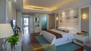A modern hotel room with a large bed, bedside table, lamp, and a view of the cityscape through the window. - Jiu Long Ying Bin Hotel (Yibin)
