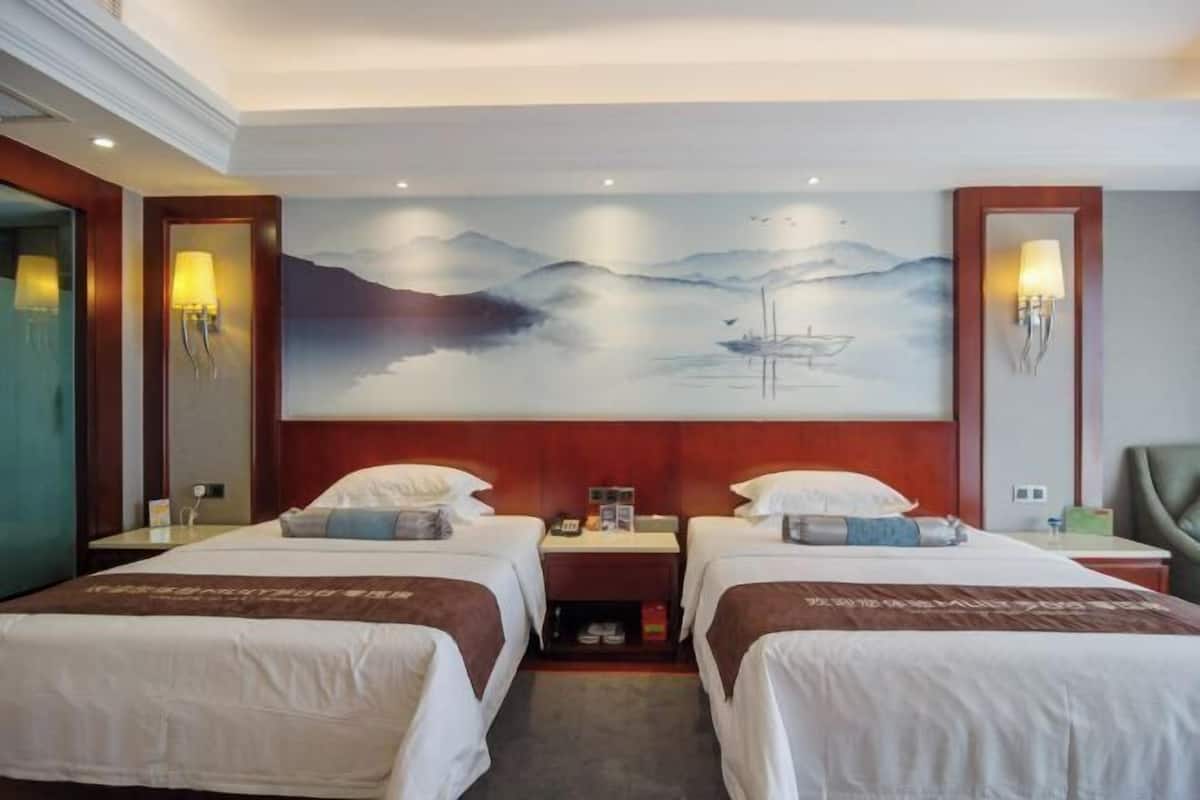 Una habitación de hotel con dos camas, un cuadro de un paisaje montañoso y un cabecero de madera.