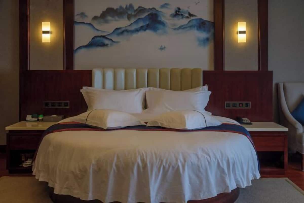 Una habitación de hotel con una cama grande, dos mesitas de noche y un cuadro colgado en la pared.