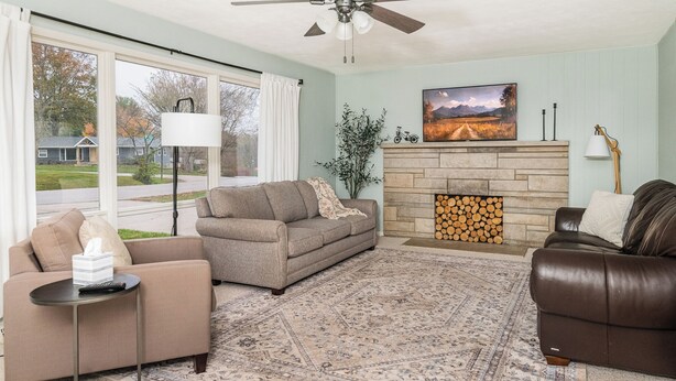 A living room with a sofa, armchair, and a fireplace. - Cozy, Roomy Ranch near IU Stadiums (Bloomington)