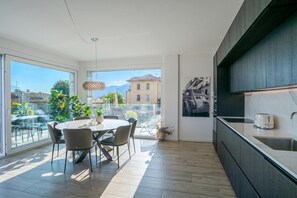 A modern kitchen with a dining area, large windows, and a view of the city. - Modern House Apartment 4, Menaggio, Italy (Menaggio)