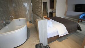 A modern hotel room with a large bed, a separate bathroom with a bathtub, and a flat-screen TV mounted on the wall. - sinweier hotel (Mianyang)