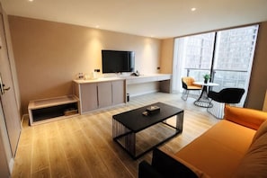 A modern living room with a sofa, coffee table, TV, and a balcony with seating. - sinweier hotel (Mianyang)