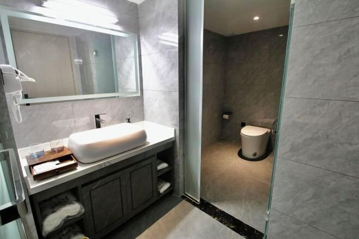 Un bany modern amb plat de dutxa de vidre, un lavabo blanc i un vàter.