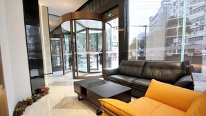 A lobby with a revolving door, a leather sofa, a coffee table, and a row of potted plants. - sinweier hotel (Mianyang)