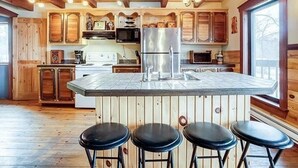 Une cuisine dotée de meubles en bois, d’un réfrigérateur en acier inoxydable et d’un coin bar avec des tabourets.
