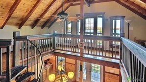 Un vaste loft doté de hauts plafonds, de poutres apparentes, d’un balcon et d’un lustre.