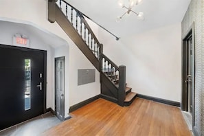 Stylish interior with a black staircase, white walls, and a door with a silver handle.