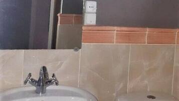 A bathroom with a sink, toilet, and a mirror.