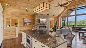 Una cocina amplia con una isla grande, techo de madera y chimenea de piedra.