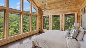 Un dormitorio con ventanas amplias, una cama y una lámpara colgante.
