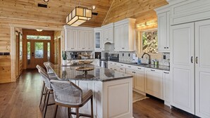 Una cocina amplia con armarios blancos, una isla grande con taburetes de bar y un techo de madera.