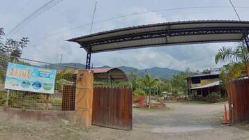 Una entrada de grava con una puerta de madera, un toldo metálico y un letrero.