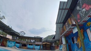 A swimming pool area with a covered seating area and a building with colorful murals.