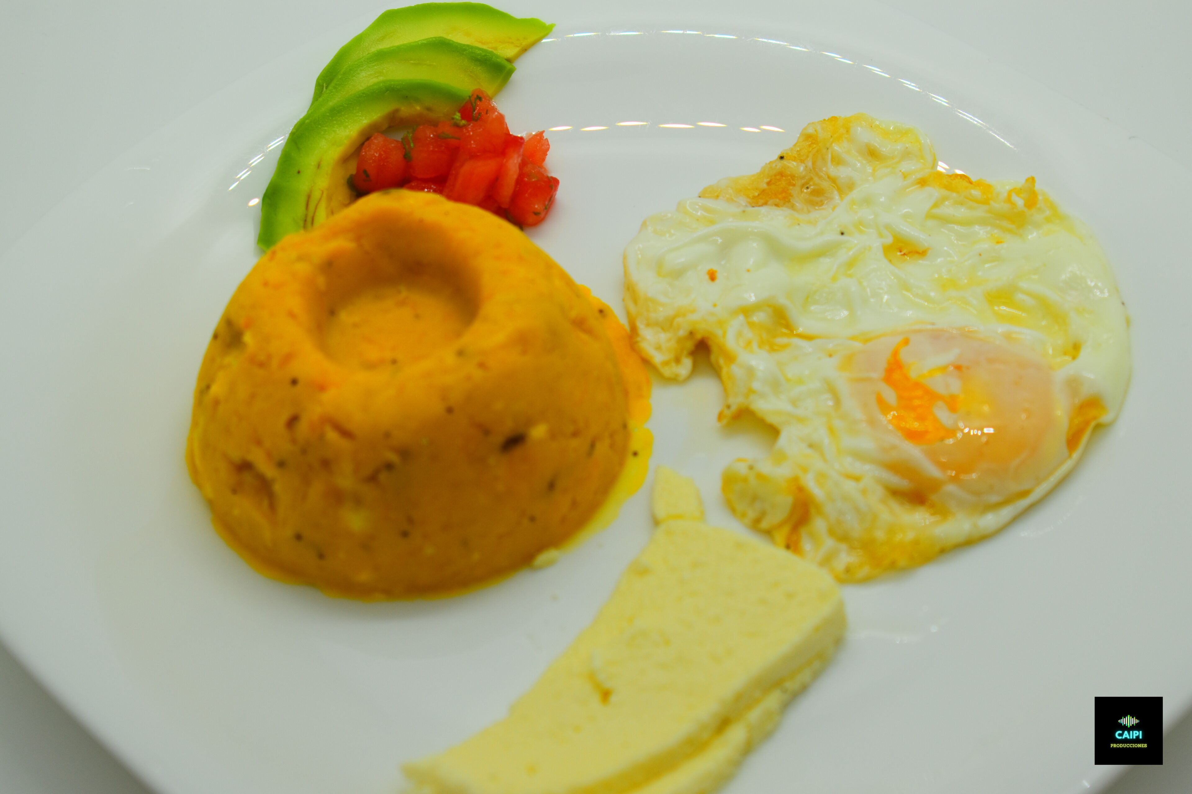 A plate with a fried egg, a slice of avocado, and a portion of what appears to be a potato dish.