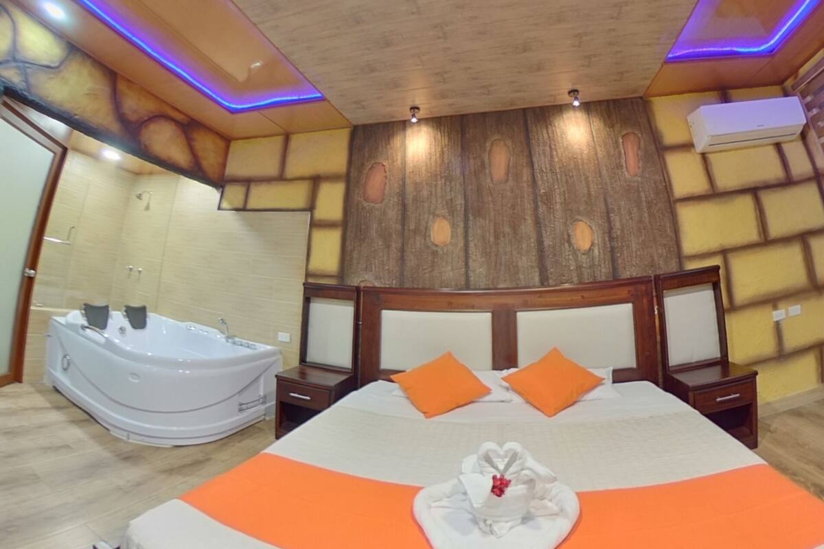 Un dormitorio con una cama grande, una bañera integrada y un techo de madera con iluminación empotrada.