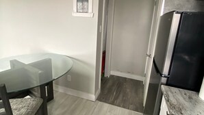 Eine moderne Küche mit einem Glastisch, dunklen Holzsesseln, einem schwarzen Kühlschrank und einem kleinen Fenster.