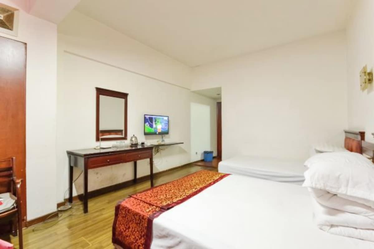 Une chambre d’hôtel avec un lit, un bureau, une télévision et un miroir.
