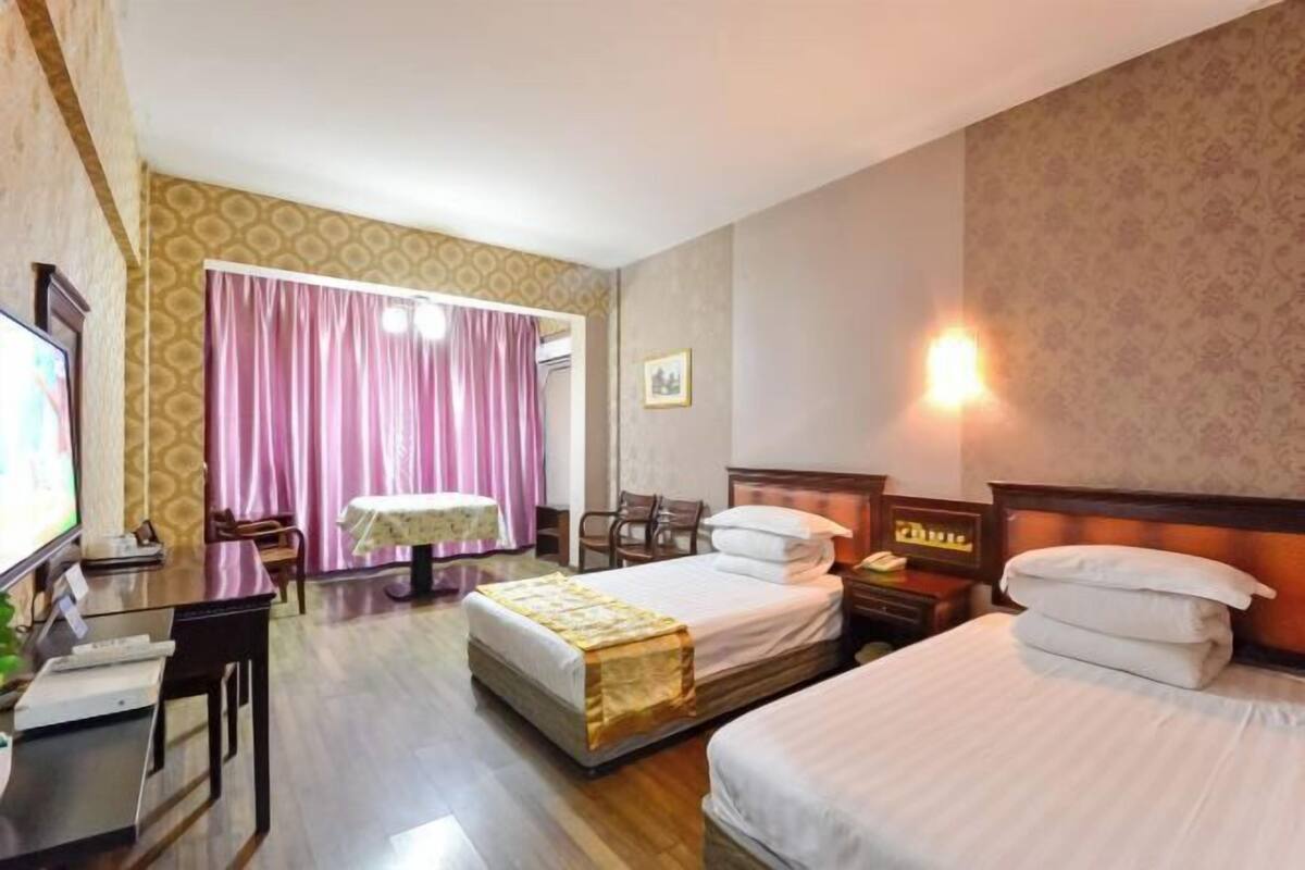 Habitación de hotel con dos camas, un escritorio, una silla, una mesa y un televisor.