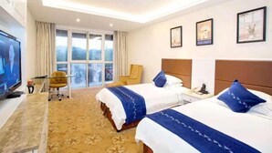 Une chambre d’hôtel avec deux lits, une télévision, un bureau et une fenêtre donnant sur un paysage agréable.