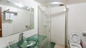 Une salle de bain avec un lavabo en verre, une douche et des toilettes.