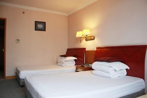 Une chambre d’hôtel avec deux lits, une tête de lit en bois, une table de chevet, une lampe et un tableau encadré au mur.