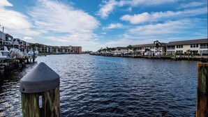 A waterfront view with boats docked, buildings along the shore, and a clear sky. - Cozy 2 Bed 2 Bath Waterfront Condo SE Cape Coral only 20 min to Ft Myers Beach (Cape Coral)