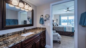 A bathroom with a granite countertop, a large mirror, and a ceiling fan. - Cozy 2 Bed 2 Bath Waterfront Condo SE Cape Coral only 20 min to Ft Myers Beach (Cape Coral)