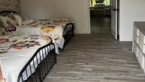 Makuuhuoneessa on kaksi sänkyä, kattotuuletin, kuviollinen matto ja näkymä parvekkeelle.