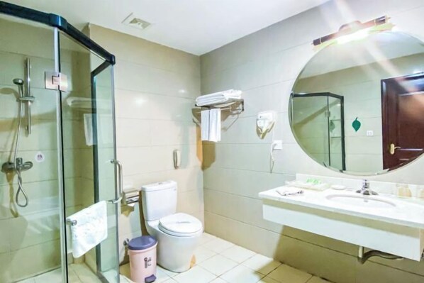 A bathroom with a glass shower enclosure, a toilet, a sink with a mirror, and a towel rack. - Hexie Hotel (Zhenxiong)