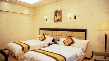 Ein Hotelzimmer mit zwei Betten, einem Kopfteil, Wandlampen, einem gerahmten Bild und einem Stuhl.