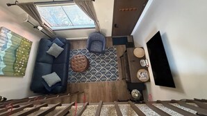 Una habitación con sofá, reposapiés, alfombra estampada y televisor.